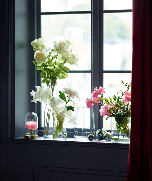 Стъклени вази с цветя на рамката на прозорец.