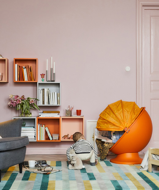 Създайте забавен детски ъгъл в вдневната със стол IKEA PS LÖMSK. Цветна дневна с детски оранжев стол и две деца, които четат и играят.