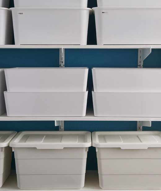 Използвай IKEA KUGGIS и SOCKERBIT кутии за съхранение за оптимално използване на пространството по рафтовете. Бели кутии за съхранение, подредени в шкаф.