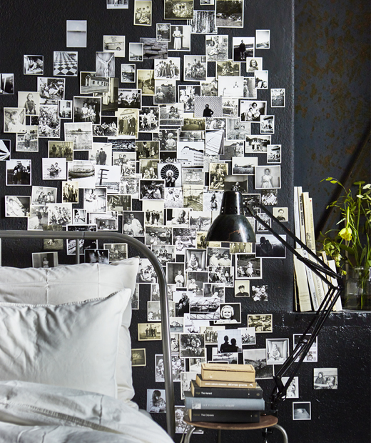 Стена на спалня, покрита с черно-бели семейни снимки.