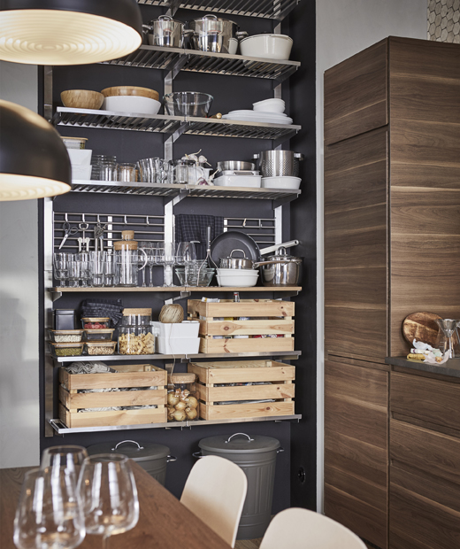 Използвай рафтове IKEA KUNGSFORS за ефикасна и достъпна кухня. Кухненски прибори и дървени кутии, съхранявани на отворен метален рафт до тъмна стена.