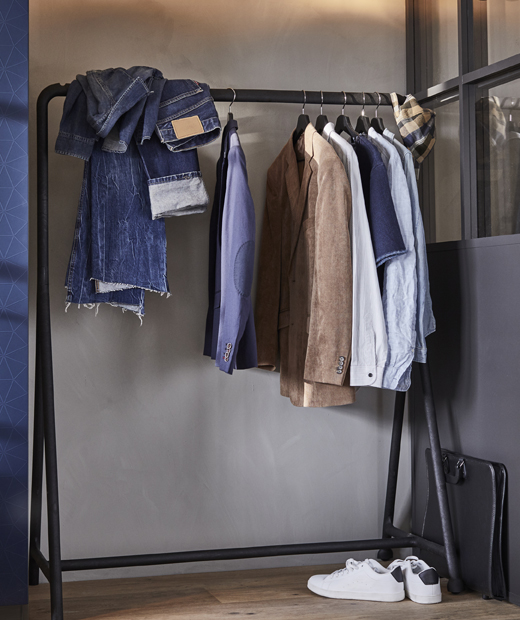 Използвай стойката за дрехи IKEA TURBO, за да покажеш дрехите си на другите. Дрехи висят на черна релса пред бледо сива стена.